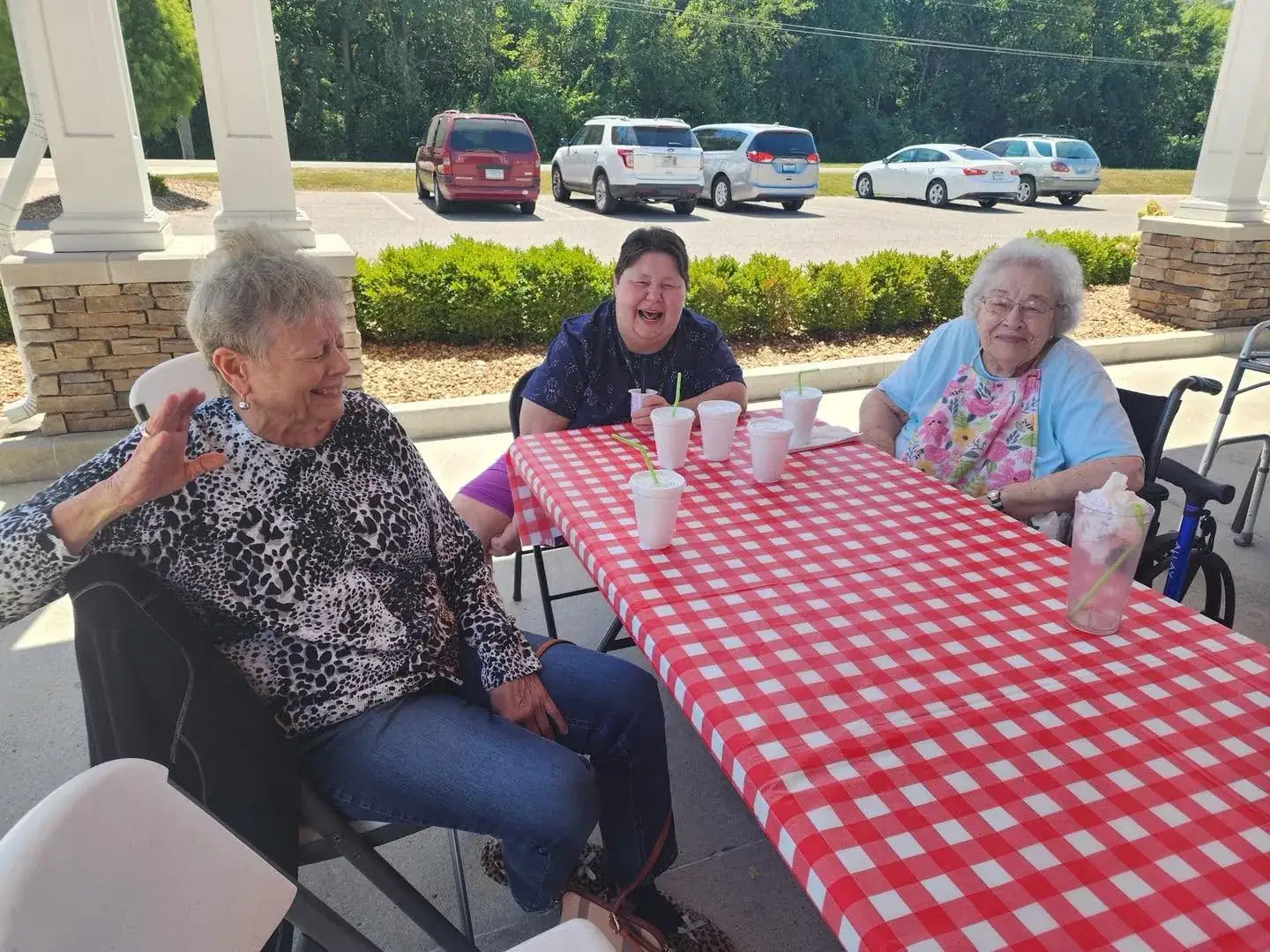 Residents sharing a laugh at a picnic table on the covered porch at Adams Lane